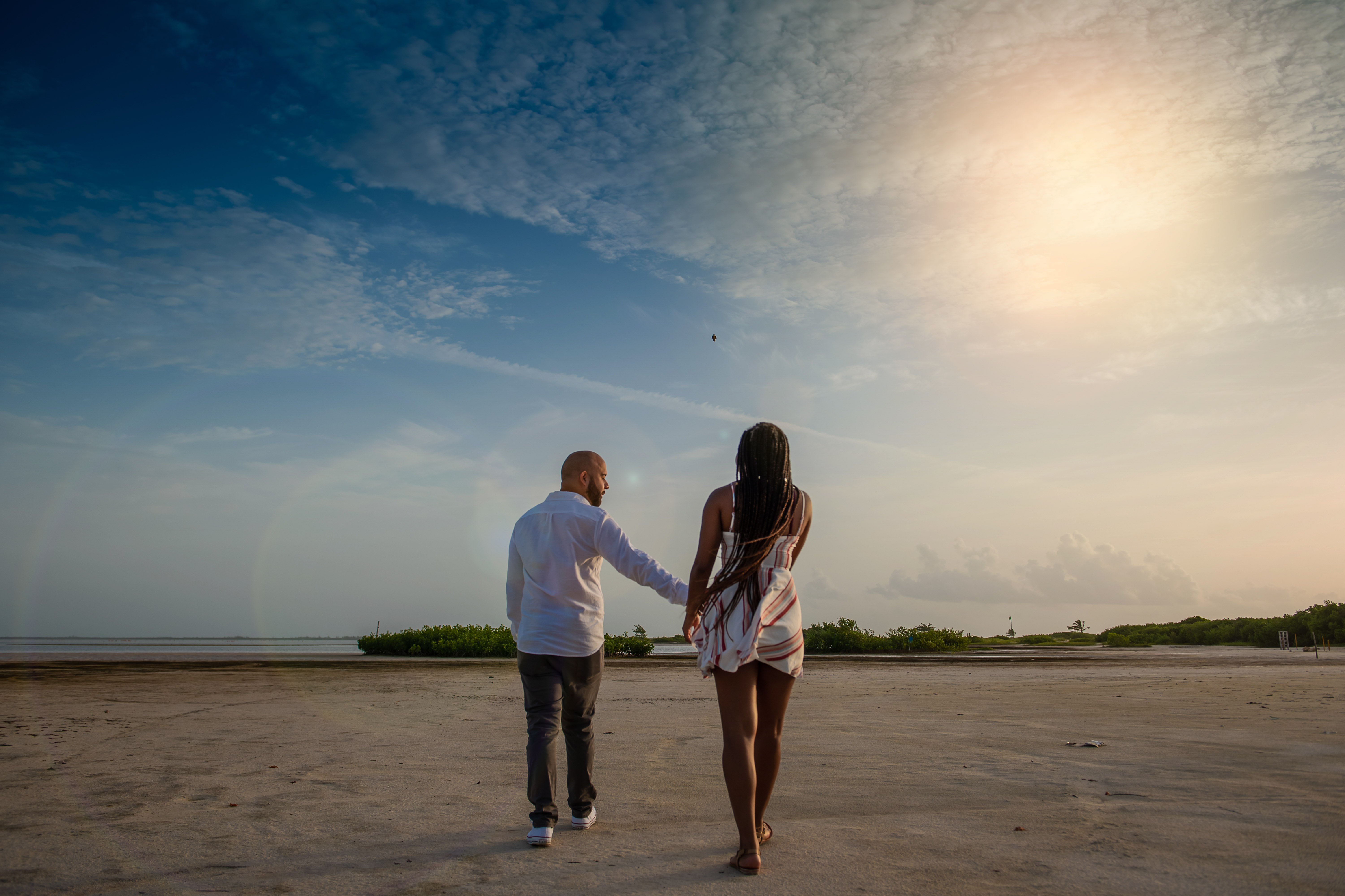 a couple walking at Isla Blanca with the sunrise holding hands at Costa Mujeres Cancun
