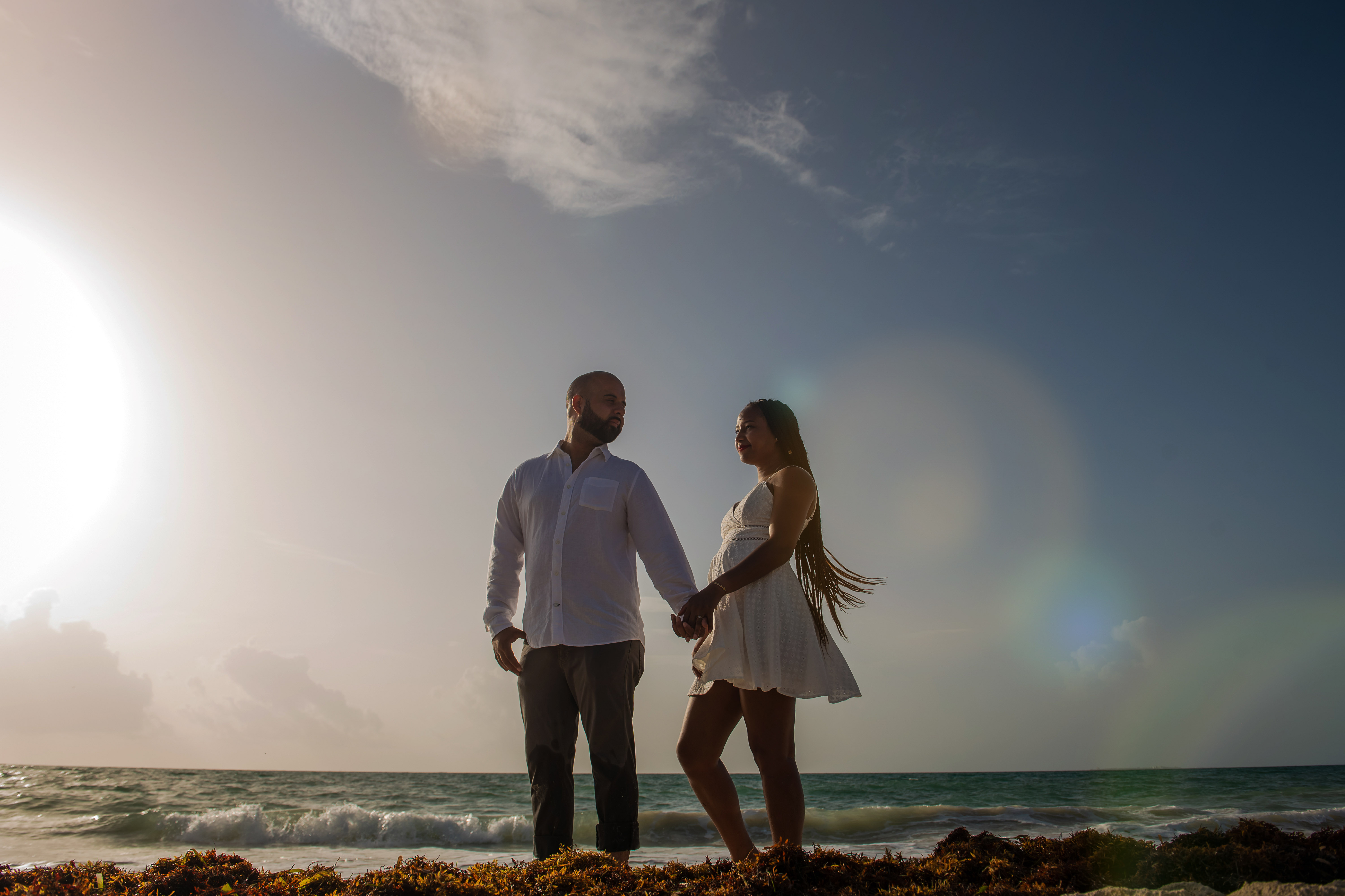 the sunrise at the beach with a couple posing with a view to the ocean at Isla Blanca Cancun and the Riu Costa Mujeres